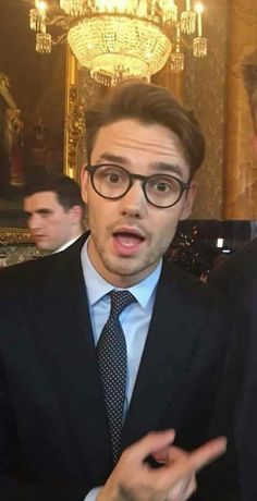 a man wearing glasses and a suit with a surprised look on his face