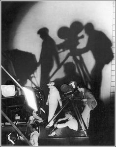 black and white photograph of people casting shadows on the wall