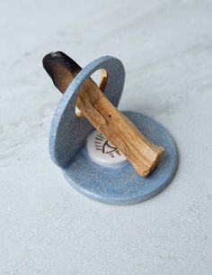 a small wooden object sitting on top of a blue plate with a piece of wood sticking out of it