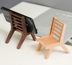 two wooden chairs sitting next to each other on top of a white table with a cell phone