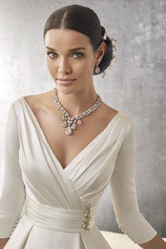 a woman in a white dress wearing a diamond necklace and matching bracelet with her hand on her hip