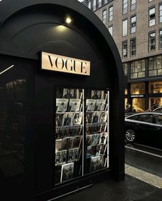 the front of a magazine store with cars parked in the street behind it on a rainy day