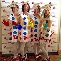 three women dressed in polka dot dresses and rubber gloves pose for a photo with their hands painted