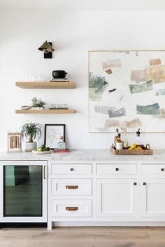 a kitchen with white cabinets and open shelvings on the wall next to an oven