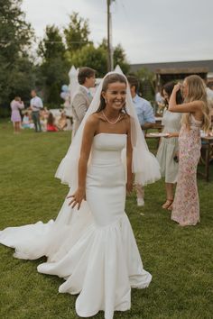 a woman in a wedding dress standing on the grass