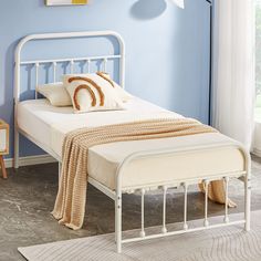 a white metal bed frame in a bedroom with blue walls and rugs on the floor