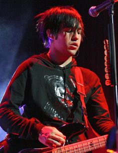 a young man holding a guitar while standing in front of a microphone