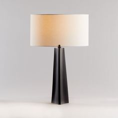 a black table lamp with a white shade on the base and a light bulb in the middle