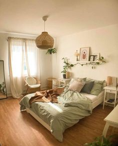 a bed sitting in a bedroom next to a white desk and chair with a plant on top of it