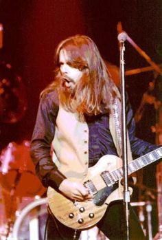 a man with long hair playing an electric guitar