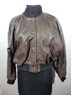 Stylish brown leather women's jacket. Refined brown leather jacket with knitted inserts. The jacket is made of durable brown leather. The jacket is sewn according to the model with enlarged shoulders that go into the sleeves, which will perfectly emphasize your strength and add convenience. The jacket fastens with decorative metal buttons. The jacket has two pockets at the bottom and one inside. A great feature of the jacket is the decorative stretch knit inserts on the collar, cuffs and bottom of the jacket, which will perfectly retain your body heat. The jacket has a nice polyester lining. The jacket is stylish, elegant and comfortable to wear, it will perfectly emphasize your unique image and keep you warm in cool weather. MEASUREMENTS Length                                49 cm  |  19, Fitted Brown Leather Jacket With Buttons, Designer Brown Leather Jacket With Button Closure, Fitted Brown Biker Jacket With Button Closure, Designer Fitted Brown Leather Jacket, Fitted Designer Brown Leather Jacket, Designer Fitted Brown Biker Jacket, Brown Leather Outerwear With Buttons, Brown Leather Jacket With Buttons For Winter, Fitted Vintage Brown Leather Winter Jacket