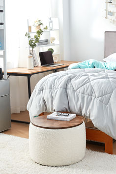 a bedroom with a bed, desk and laptop on the table in front of it