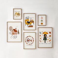 four framed pictures hang on the wall with autumn decorations in front of them, including an umbrella