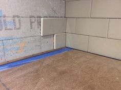 the corner of a room that is under construction with blue tape on the floor and walls