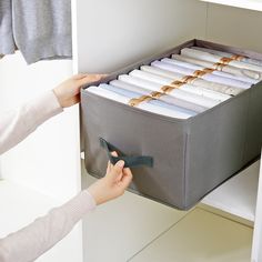 a woman is holding a file drawer with files in it and another person holds a pair of scissors