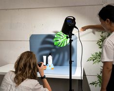 a woman is setting up a photo shoot in front of a camera and lighting equipment