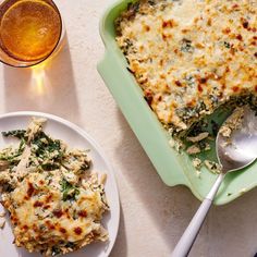 a green casserole dish with spinach and cheese next to a glass of beer