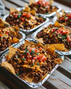 several trays filled with nachos on top of a wooden table