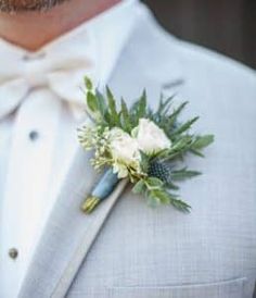 a close up of a person wearing a suit and tie with a boutonniere