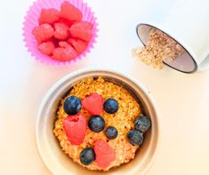 an oatmeal with blueberries and strawberries in a bowl next to a cup of cereal