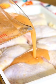 someone pouring sauce on some food in a pan