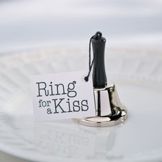 a ring for a kiss sits on a plate with a sign attached to it that says, ring for a kiss