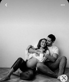 a man and woman sitting on the floor with their arms around each other as they cuddle