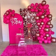 a pink and gold birthday party with balloons on the wall, cake stand and table