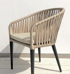 a wicker chair sitting on top of a wooden floor next to a white wall