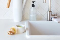 a white sink sitting next to a faucet and soap dispenser