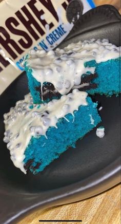 blue cake with white frosting on a black plate next to a hershey bar