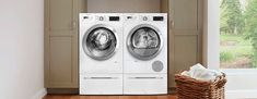 a washer and dryer sitting in front of a window next to a basket