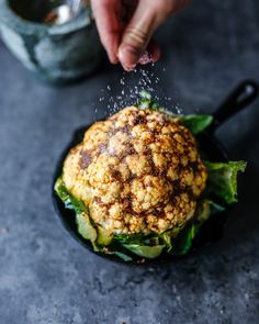 a person sprinkling seasoning on a cauliflower burger