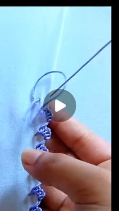 someone is crocheting the stitches on a piece of blue fabric with a needle