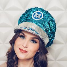 a woman wearing a blue hat with sequins on the front and side, smiling at the camera