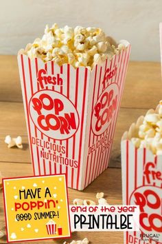 three popcorn boxes filled with popcorn sitting on top of a wooden table