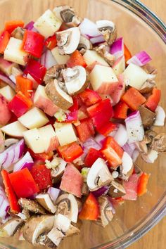 a glass bowl filled with chopped vegetables on top of a wooden table