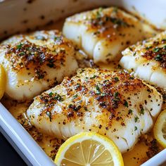 some fish with lemon slices and seasoning in a white dish