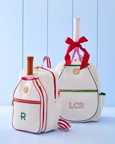 two white bags with red and green trim, one has a wine bottle in it