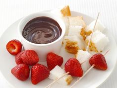 strawberries and marshmallows are on a plate with chocolate dip in the middle