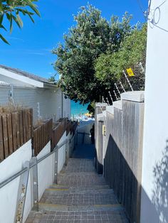 an alley way leading to the beach with houses on either side and trees in the background