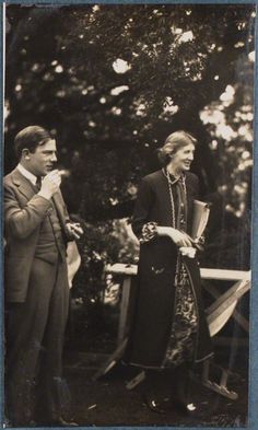 an old black and white photo of two people standing next to each other