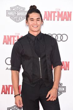 a man in black shirt and tie standing on red carpet with his hands in his pockets