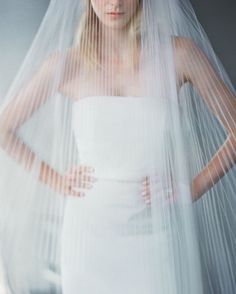 a woman in a white dress and veil with her hands on her hips looking at the camera