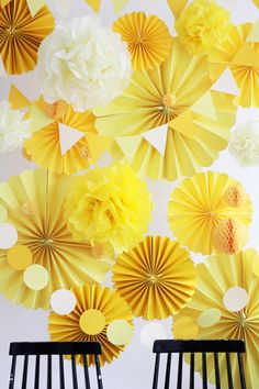 two black chairs sitting in front of a wall with yellow and white paper flowers on it