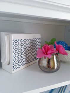 two vases with pink flowers sit on a white shelf next to other decorative objects