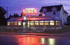 the diner is lit up at night with its neon sign on it's roof