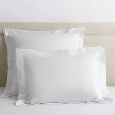 two white pillows sitting next to each other on a bed