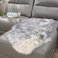 a grey leather couch with a gray and white fur rug on the back of it