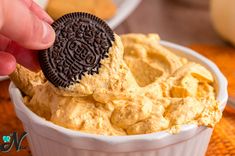 an oreo cookie being dipped into a bowl of humongous dip with peanut butter